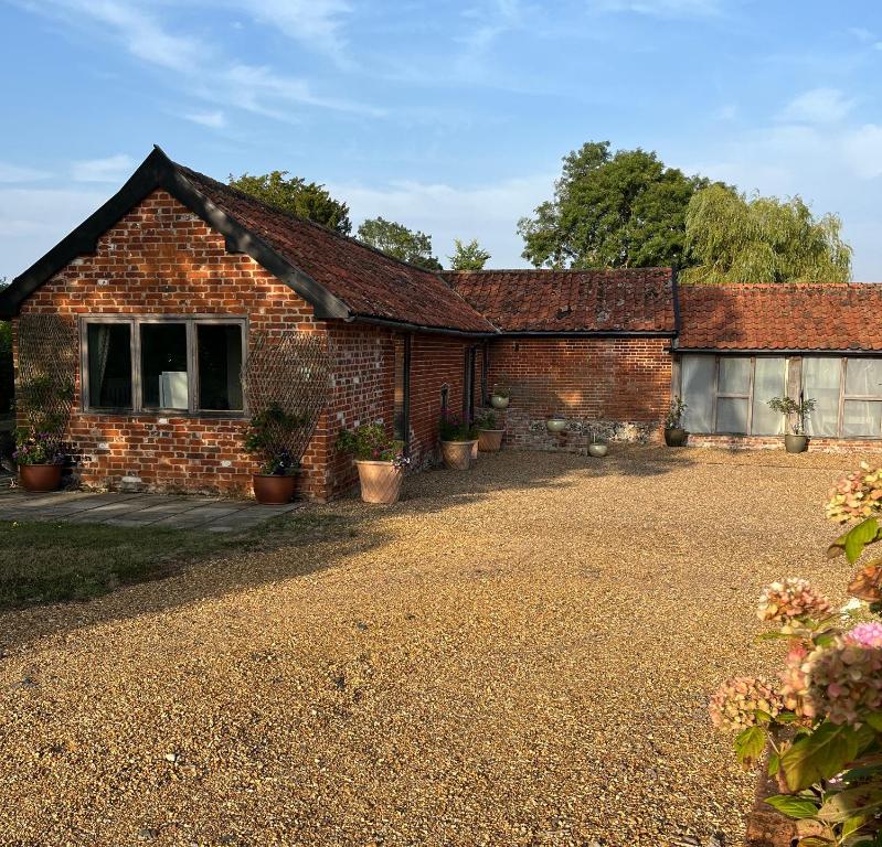 Oak Grange holiday cottage في Hoxne: منزل من الطوب مع نباتات الفخار أمامه