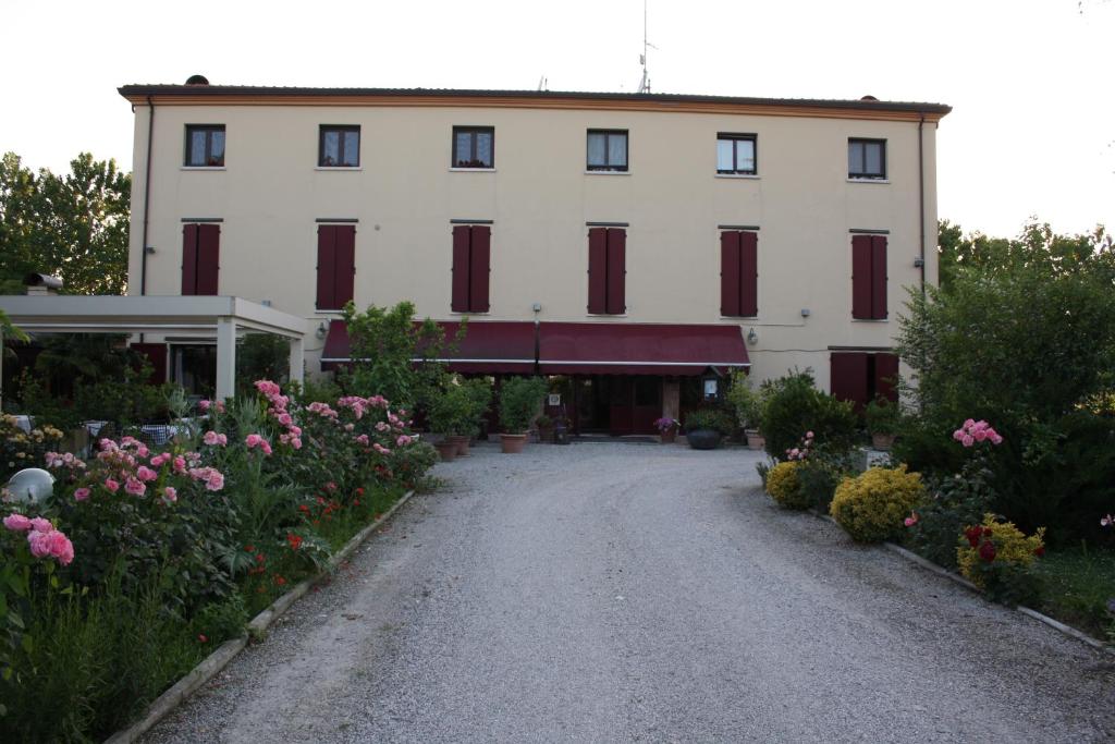 - un grand bâtiment blanc avec des fenêtres rouges et des fleurs dans l'établissement Villa Belfiore, à Ostellato