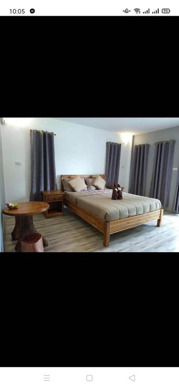 a bedroom with a bed and a wooden table at เดอะนิรันดร์ เกสท์เฮ้าส์กาญจนบุรี in Ban Chuk Yai Yuan