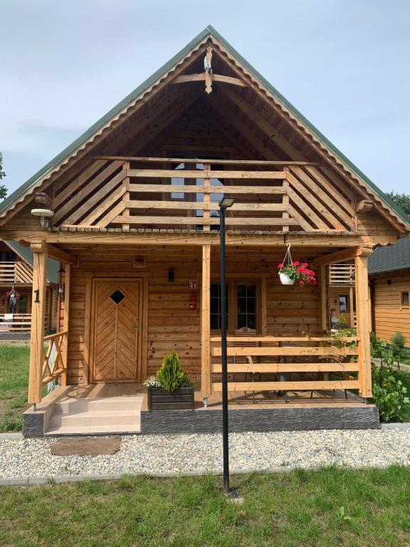 a large wooden cabin with a porch and stairs at Domki Letniczówka Kołobrzeg nad morzem in Grzybowo