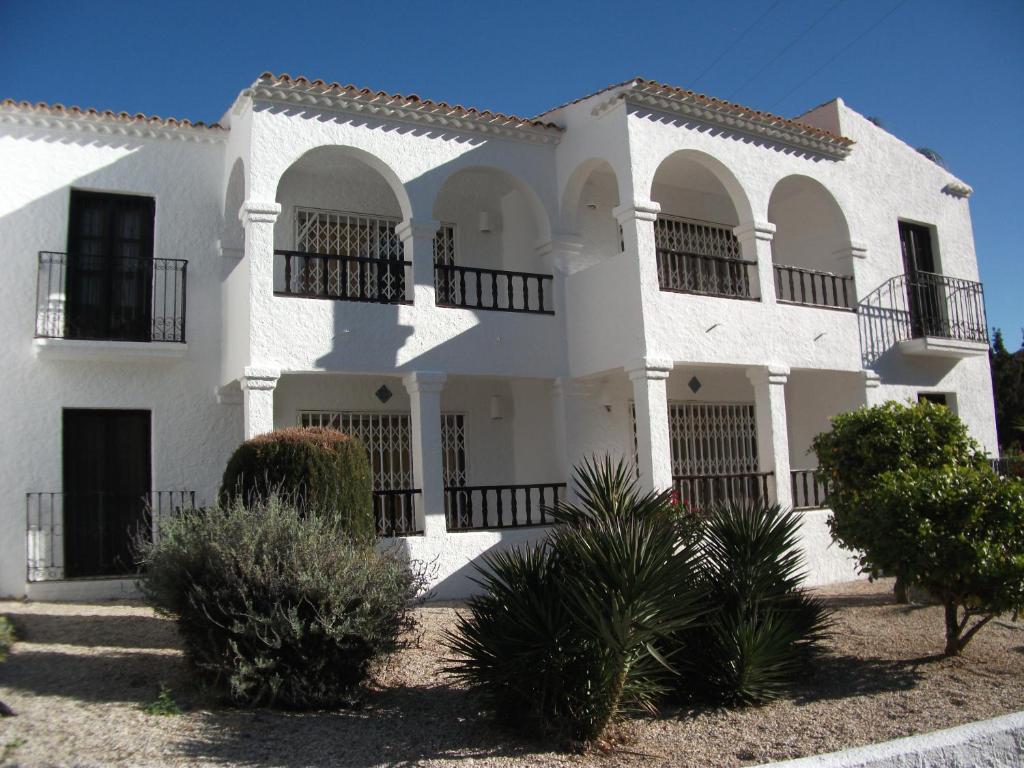 a white house with black balconies and trees at La Parata Apartments in Mojácar