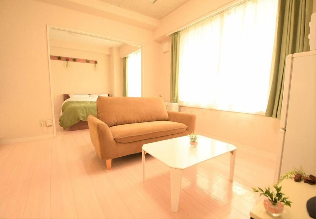 a living room with a chair and a table and a bed at E-Horizon北2条ビル in Sapporo