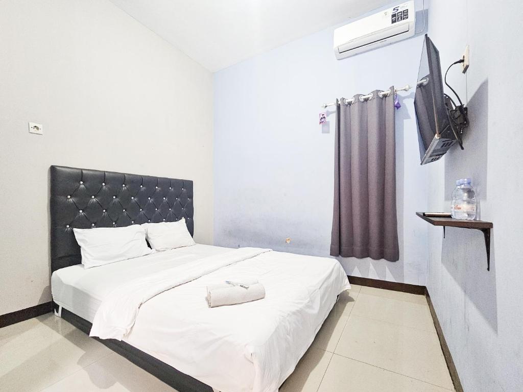 a bedroom with a white bed with a black headboard at Homestay Sido Joyo near Sunrise Mall Mitra RedDoorz in Mojokerto