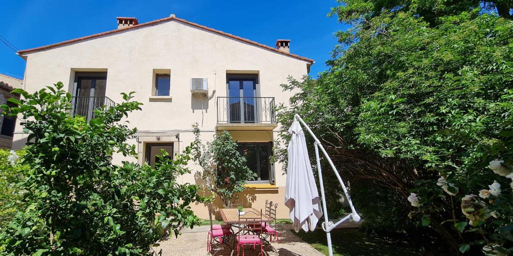 a house with a table and an umbrella in front of it at Maison "La Fleur d'oranger" climatisée, classée 3 étoiles, jardin clos, box internet in Saint-Féliu-dʼAmont