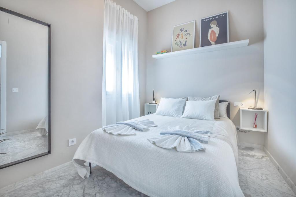 - une chambre blanche avec un lit blanc et un miroir dans l'établissement El Oasis de San Pedro, à Cordoue