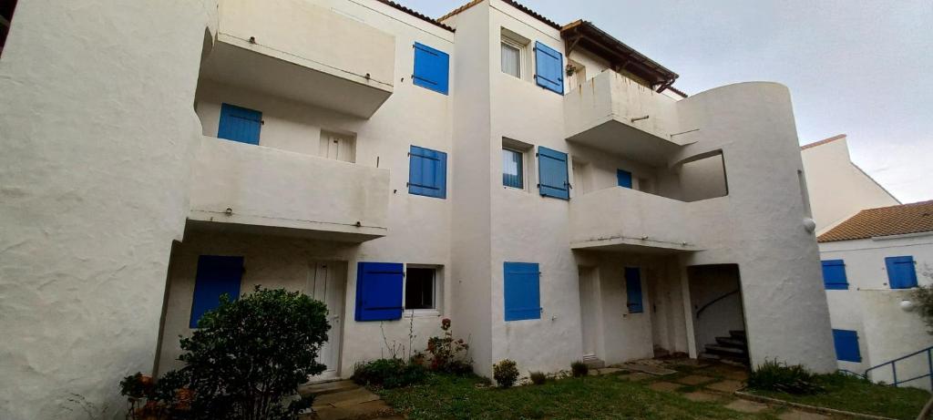 - un bâtiment blanc avec des fenêtres bleues dans l'établissement Le cocon du port Appartentre port et plages, à LʼHerbaudière