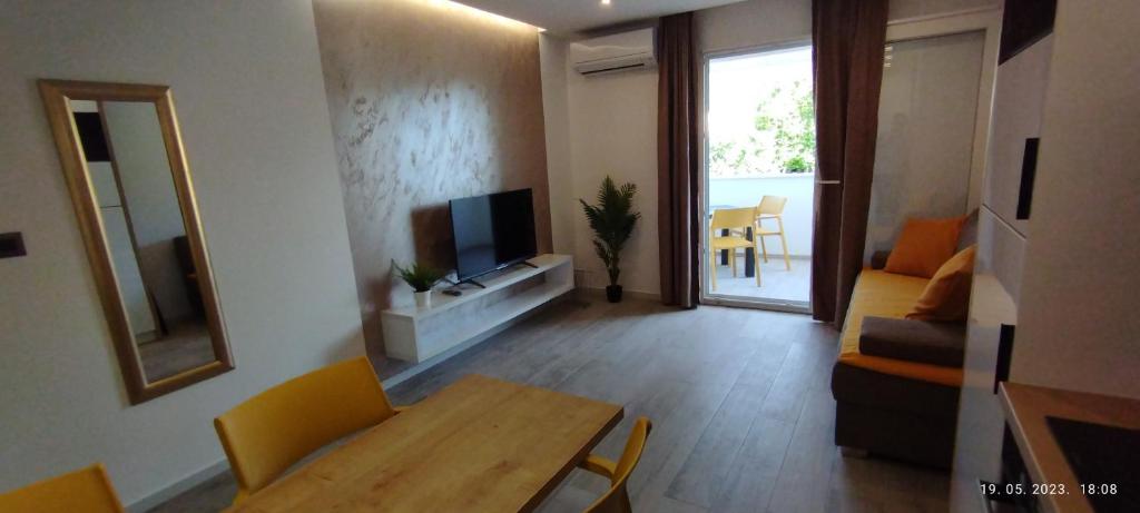 Una sala de estar con un sofá, una mesa y un televisor. en Beach apartments Promajna, en Promajna