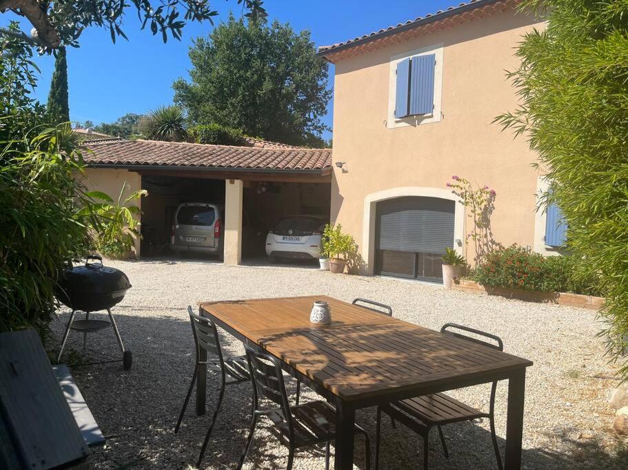 une table et des chaises en bois devant une maison dans l'établissement Sport et nature aux dentelles, à Aubignan