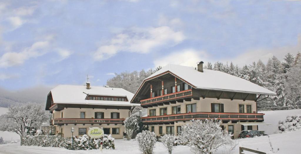 a large building with snow on top of it at Hotel Scherer in Valdaora