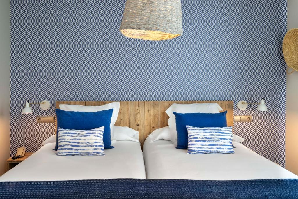 a bedroom with two beds with blue and white pillows at Vincci Puertochico in Santander