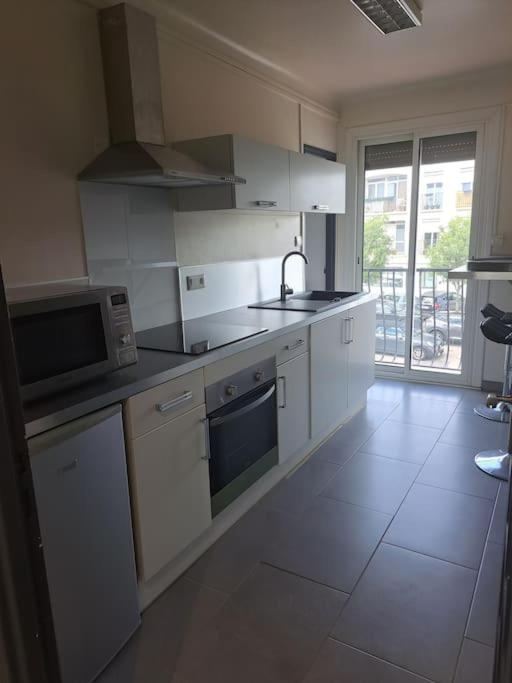 une cuisine avec des appareils blancs et une grande fenêtre dans l'établissement Joli T3 3 min gare Perpignan, à Perpignan