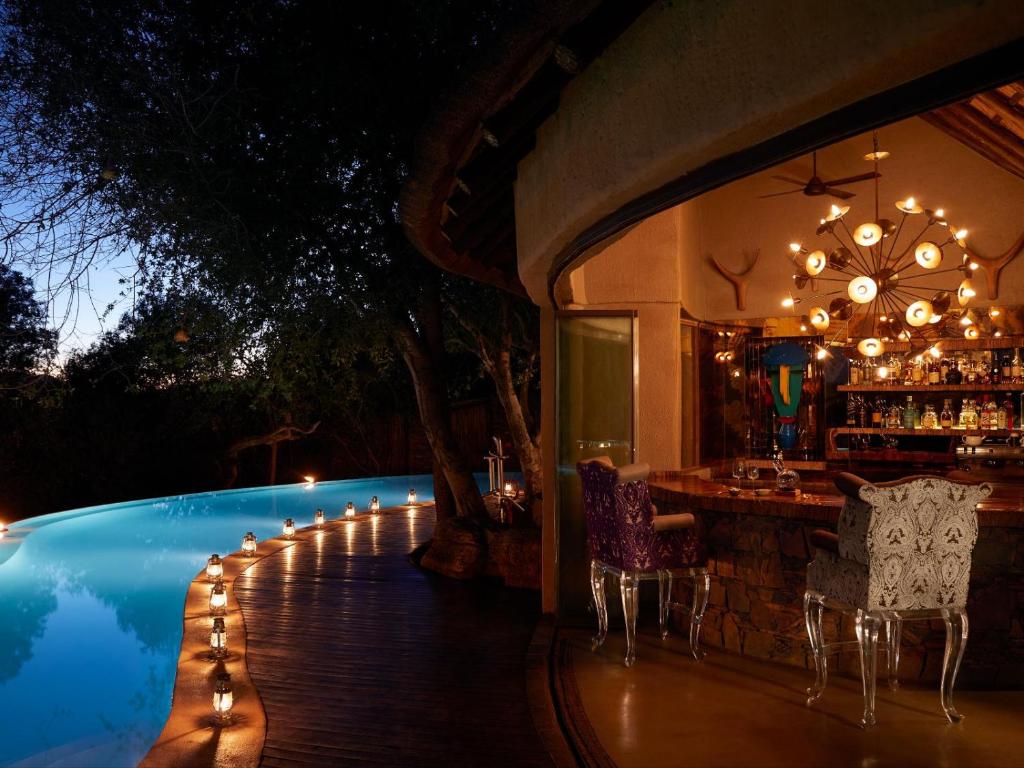 a bar next to a swimming pool at night at Molori Safari in Derdepoort