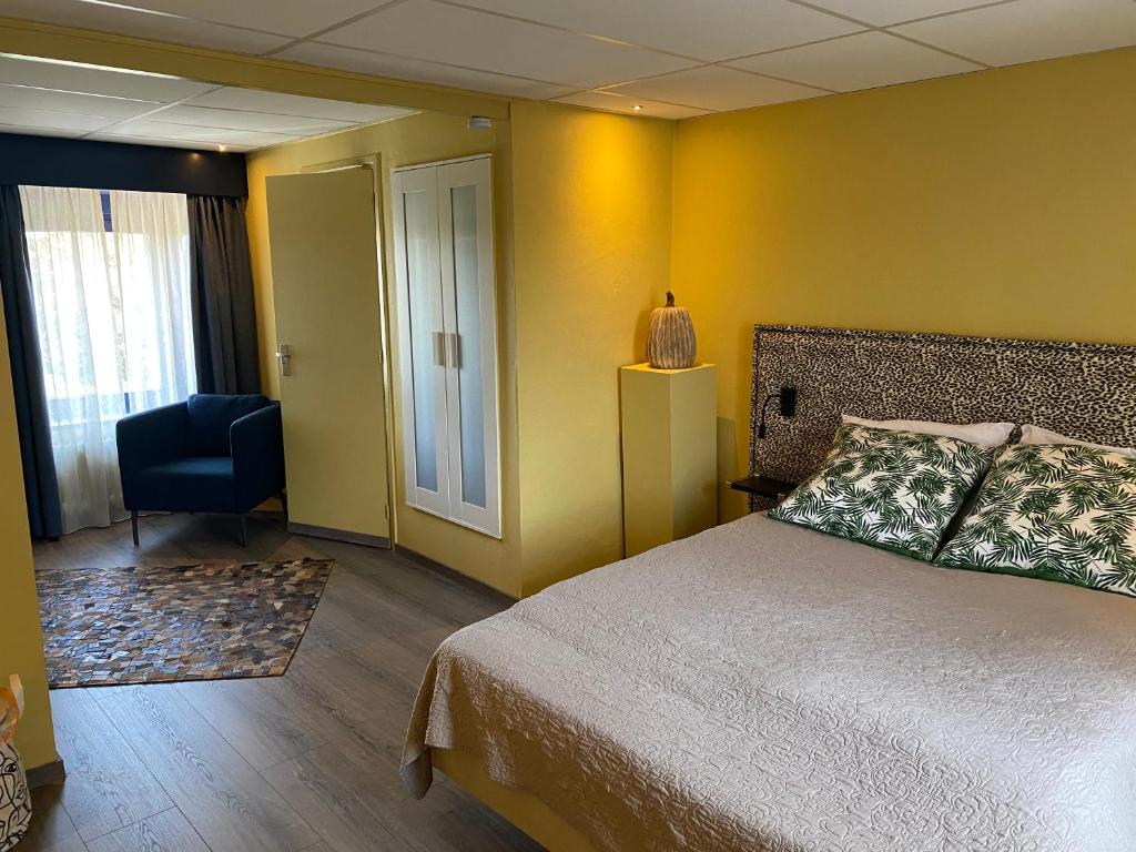 a bedroom with a bed and a chair and a window at De Post B&B Restaurant in Klimmen
