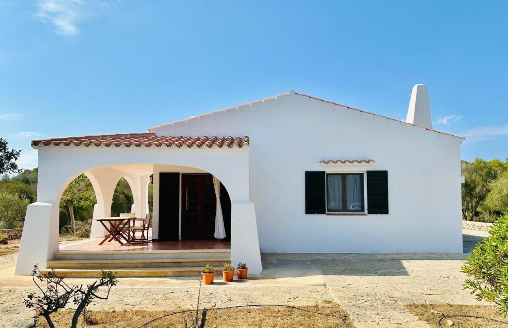 a white house with a patio in front of it at Marina - Casa de campo cerca de Ciutadella in Cala Blanca