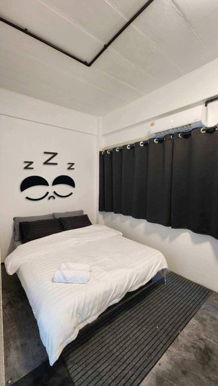 a bedroom with a bed with a face drawn on the wall at 2Sleep DMK Airport Bangkok in Ban Ko