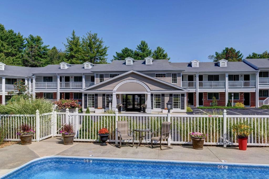 a house with a white fence and a swimming pool at Port Inn & Suites Kennebunk, an Ascend Collection Hotel in Kennebunk