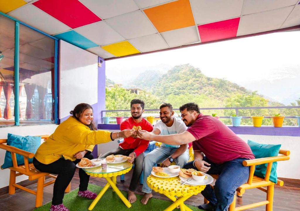 a group of people sitting around a table shaking hands at ZoukStayz in Rishīkesh