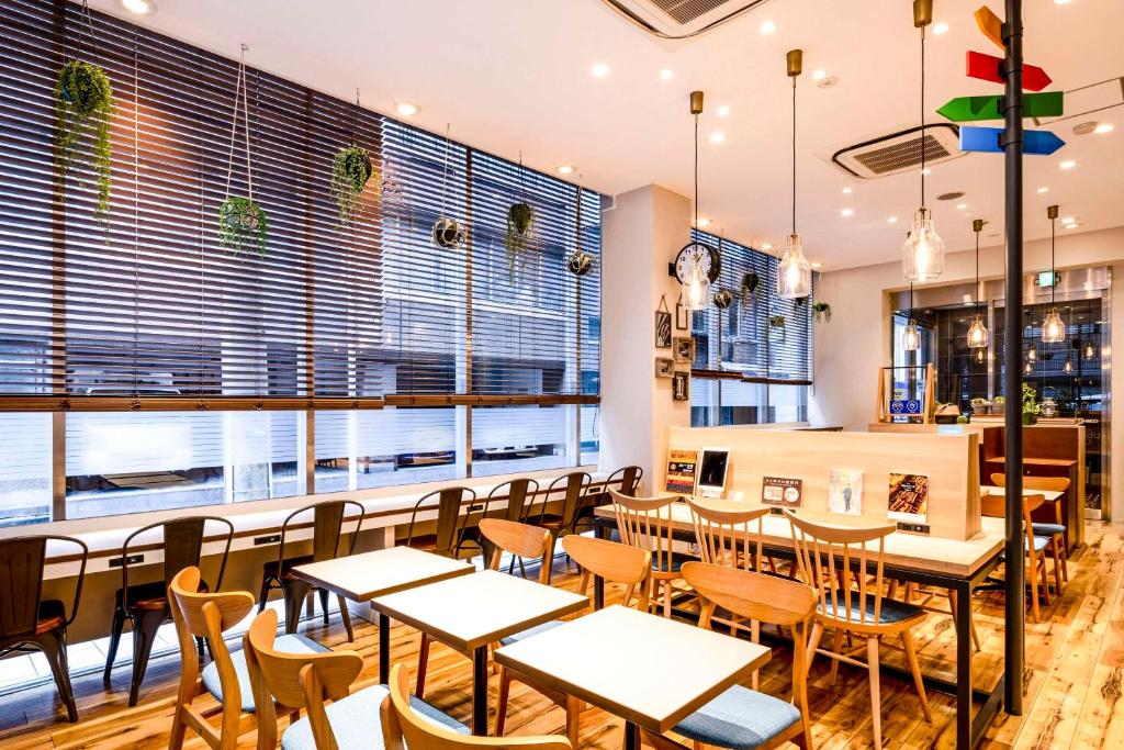 a restaurant with tables and chairs and windows at Comfort Hotel Tokyo Kanda in Tokyo