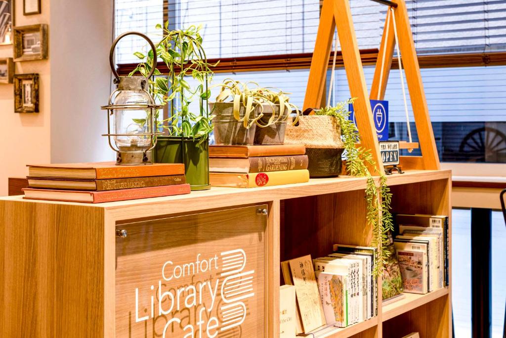 a book shelf with books and plants on it at Comfort Hotel Tokyo Kanda in Tokyo