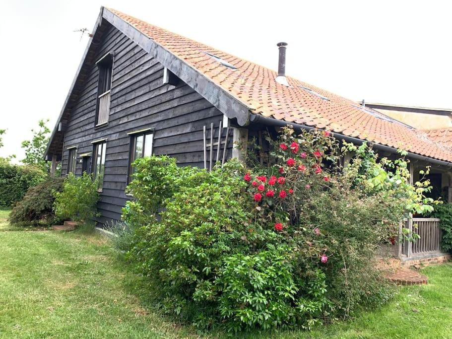a black house with red roses in front of it at Samphire Cottage in Stiffkey
