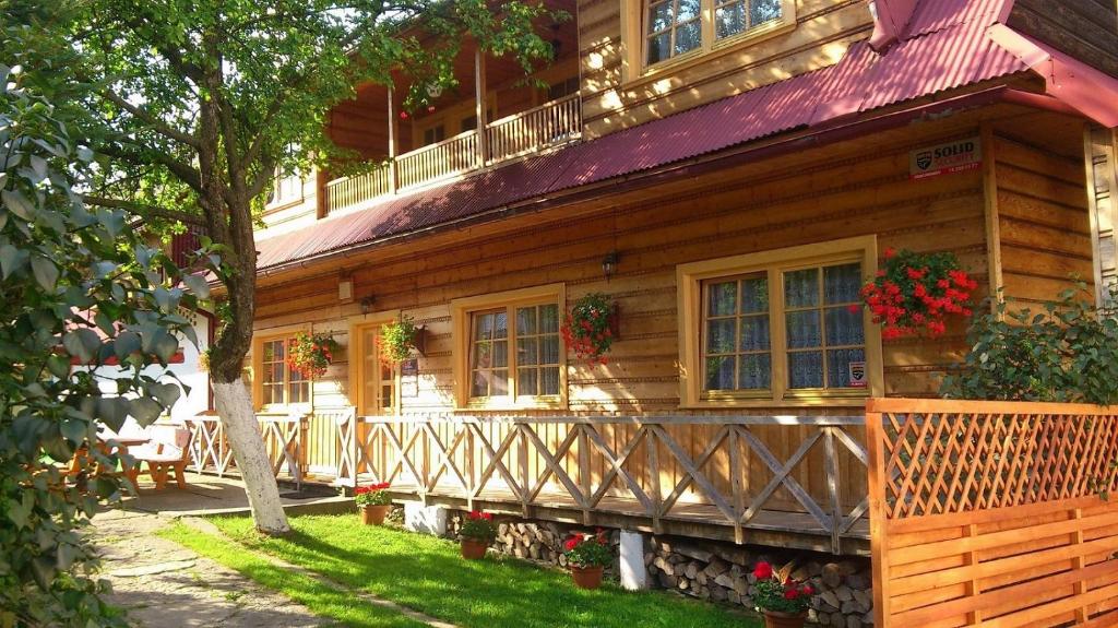 una casa de madera con flores a un lado. en Agroturystyka Sarenka, en Podsarnie