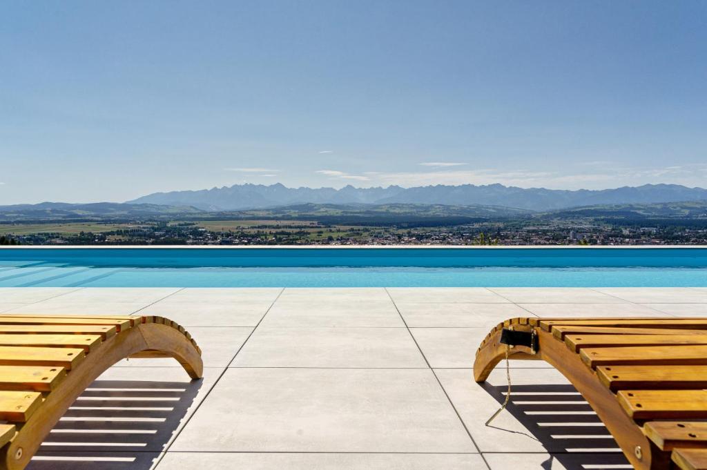 two benches sitting on top of a building with the water at Villa Revere - luksus w sercu Podhala in Nowy Targ