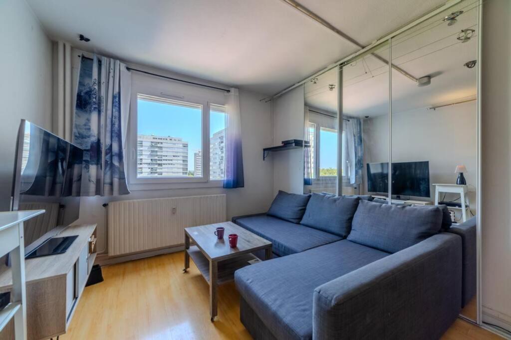 un salon avec un canapé bleu et une table dans l'établissement Appart T2 à 5 min Parc Tete d'or - Parking privé, à Villeurbanne
