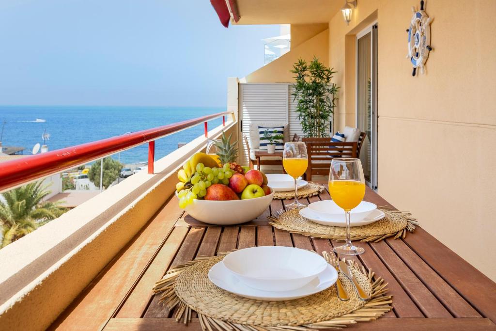a table with two glasses of wine and fruit on a balcony at Blue Garden - cozy apartment with Atlantic views in Puerto de Santiago