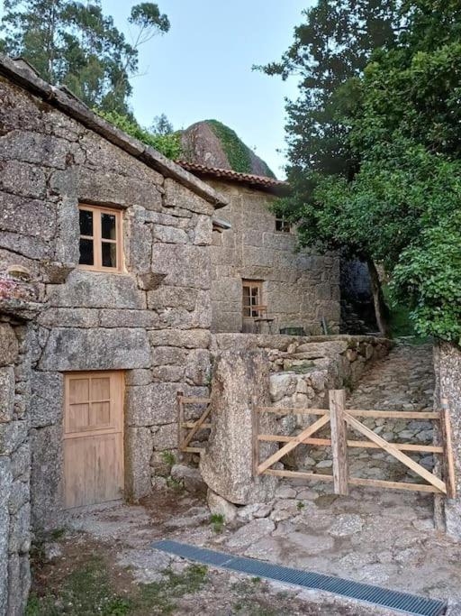 an old stone house with a wooden door and a gate at Levada da Breca - Turismo Rural in Ervedeiros