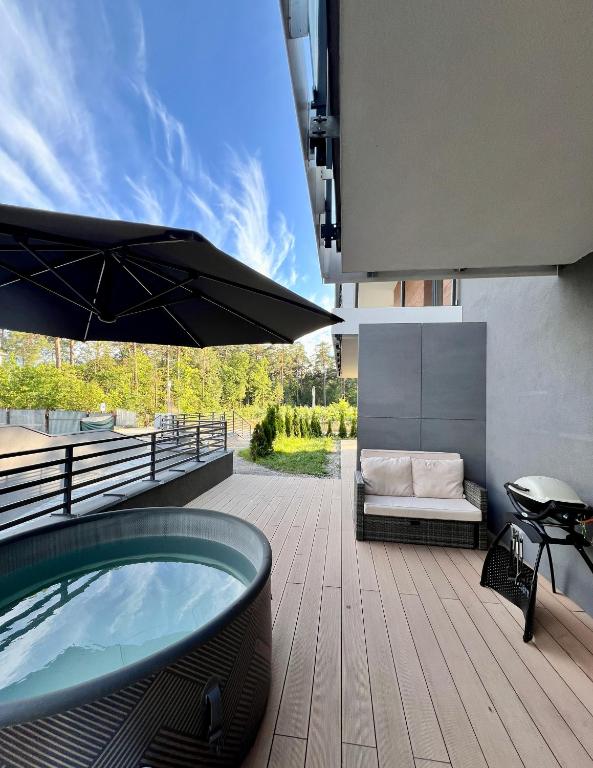 a hot tub sitting on a deck with an umbrella at Marina Augustów - BRYZA in Augustów