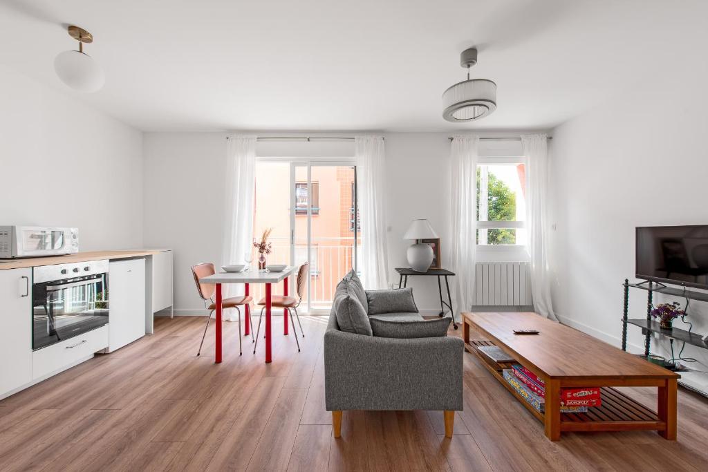 - un salon blanc avec une table et une chaise dans l'établissement L'Armagnac T2 proche gare avec parking gratuit, à Toulouse