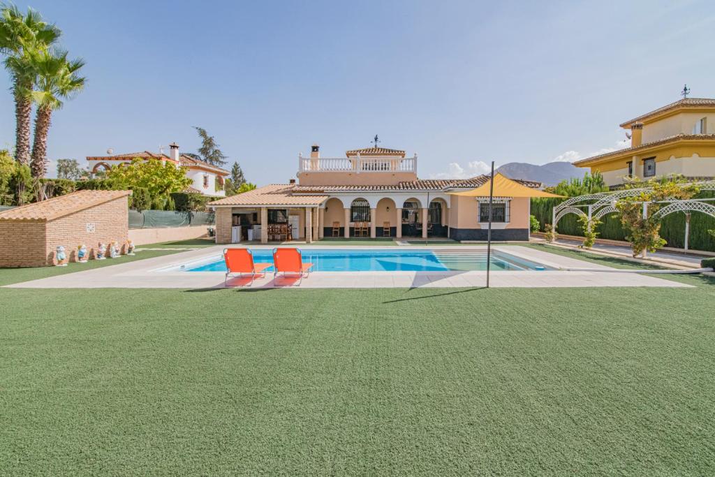 a house with a swimming pool and two lawn chairs at Cortijo El Paraíso Granada in Atarfe