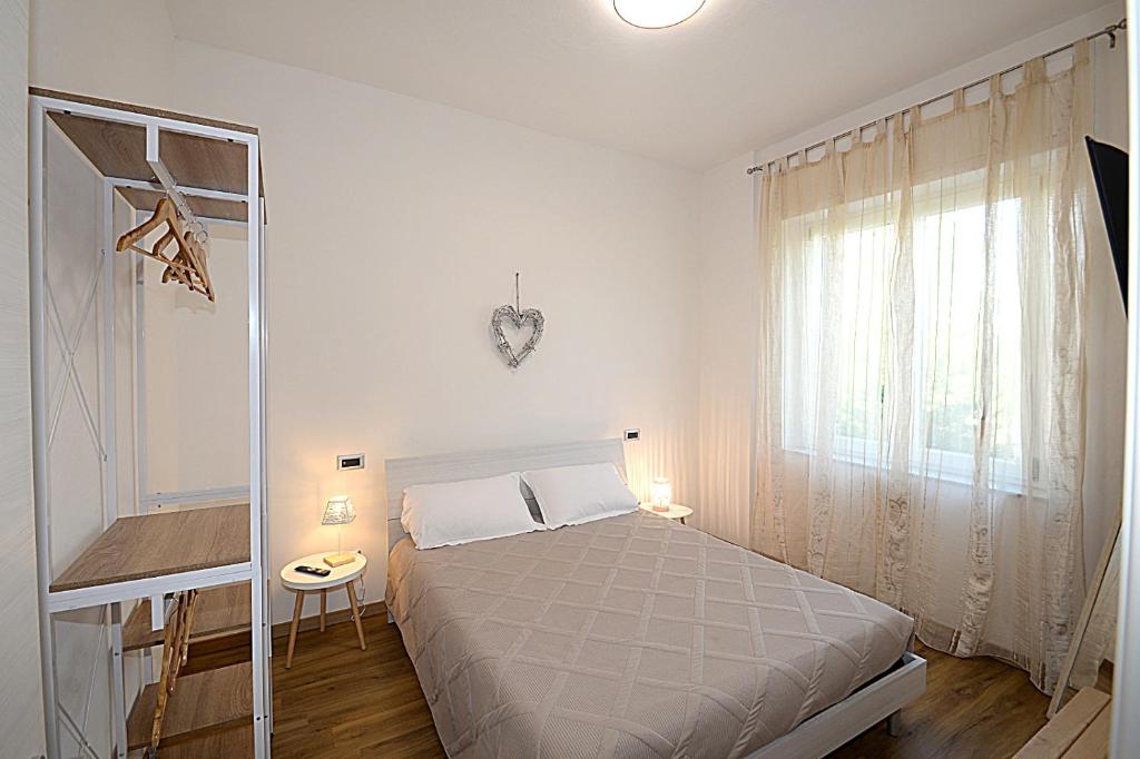 a white bedroom with a bed and a window at Casa Parisina in Chianciano Terme