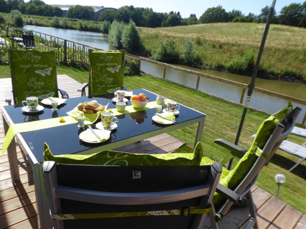 a table with food on a deck with a view of a river at Achtsamkeit - Nordhorn in Nordhorn
