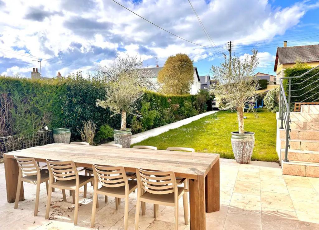 une table et des chaises en bois sur une terrasse dans l'établissement Villa de charme avec grand jardin centre Trouville sur mer, à Trouville-sur-Mer
