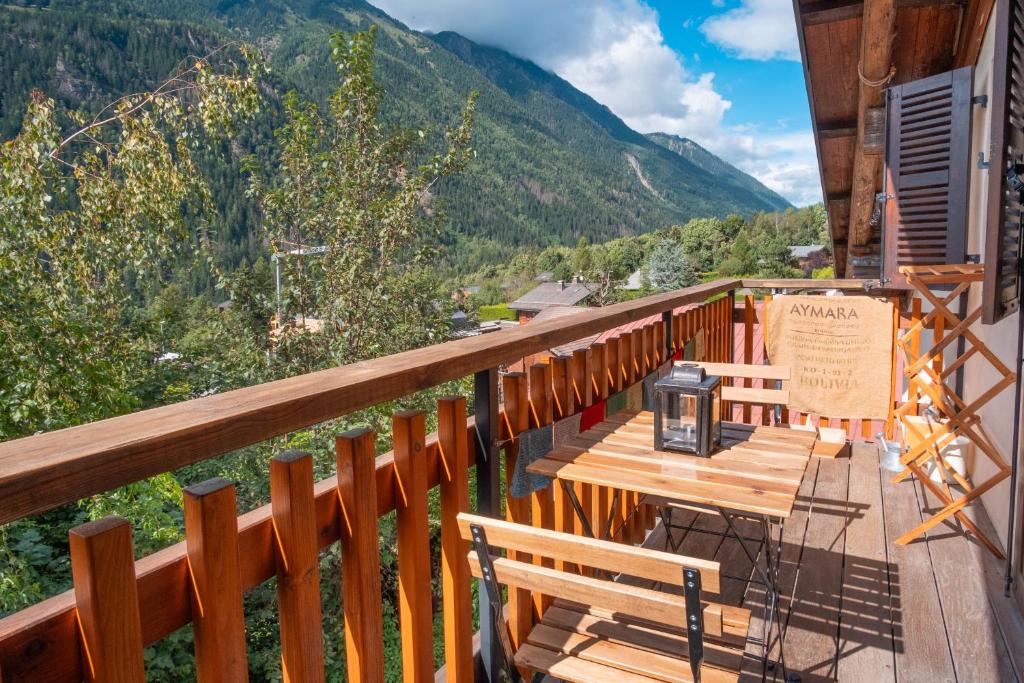 une terrasse en bois avec des bancs sur un balcon avec des montagnes dans l'établissement Le Hameau de Taconnaz - Calme - Charme, aux Houches
