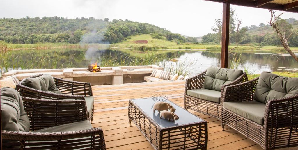 een terras met stoelen en een hond op een tafel bij Botlierskop Bush Villas in Sandhoogte