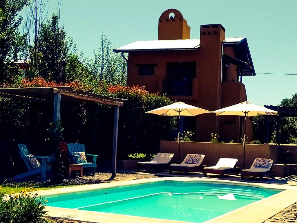 ein Swimmingpool mit Stühlen und Sonnenschirmen neben einem Haus in der Unterkunft La Cambicha Ranchos in Los Reartes