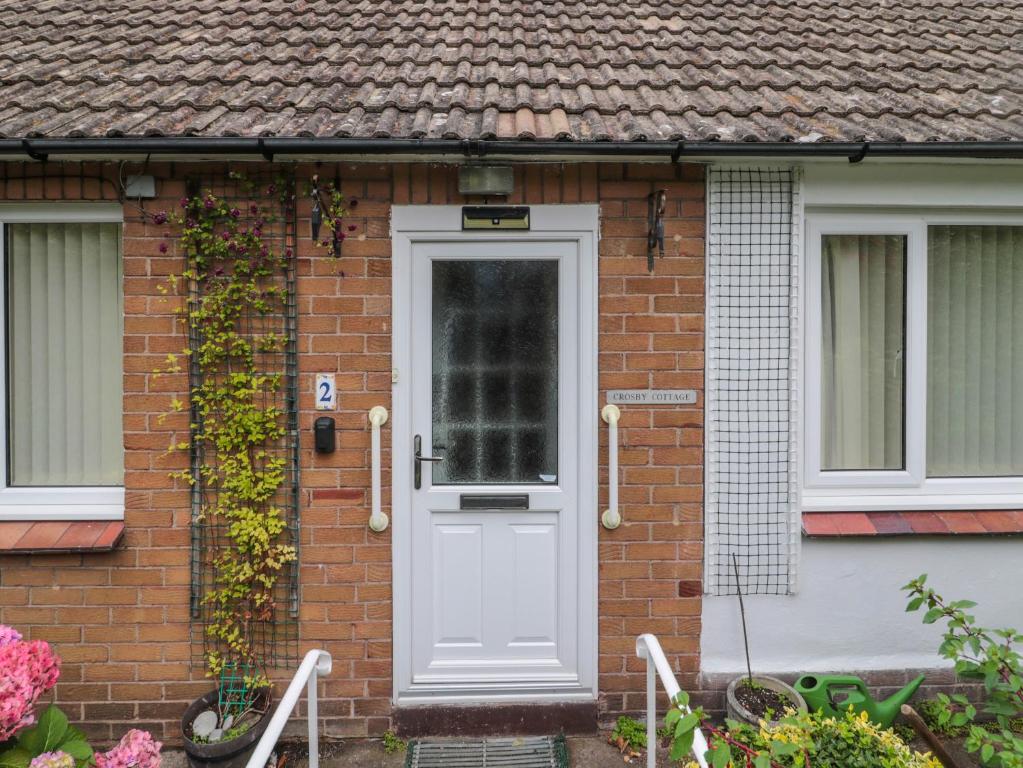a brick house with a white door at Crosby Cottage in Wooler