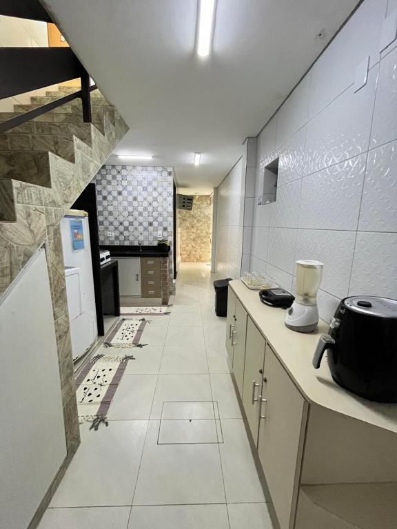 a kitchen with white tile walls and a long hallway at Paraíso Olindense in Olinda