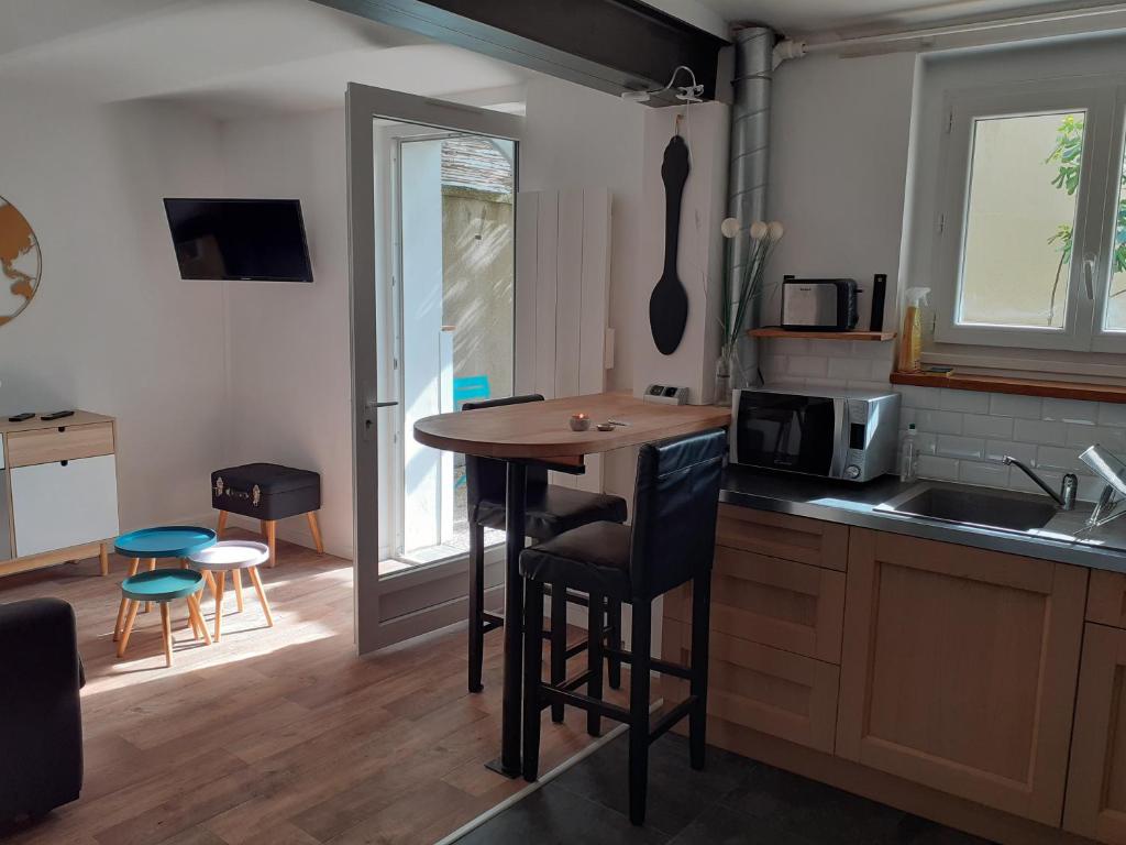 une cuisine avec un comptoir, une table et des chaises dans l'établissement Joli F2 tout confort avec jardin, à Vichy
