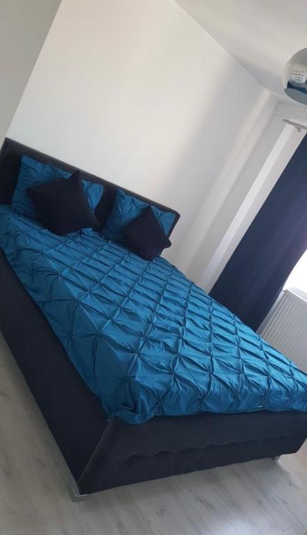 a bed with blue sheets and pillows in a room at Apartment 2 camere 1,3 km Promenada Mall Capacitate 4 persoane in Craiova
