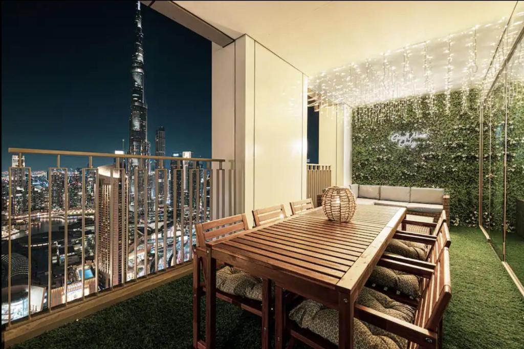 Hotel Dubai Mall Connection - Burj Views - Turf Balcony, a balcony with a wooden table and a view of a city at Dubai Mall Connection - Burj Views - Turf Balcony in Dubai