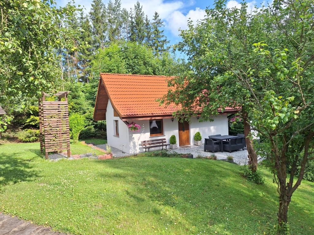una piccola casa bianca con un tetto arancione in un cortile di Domek Nad Strumykiem a Duszniki Zdrój