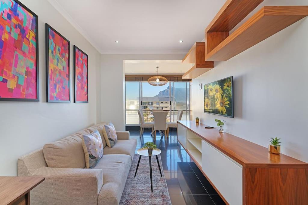 una sala de estar con un sofá y una mesa en Modern Cape Town Beach Apartment, en Ciudad del Cabo