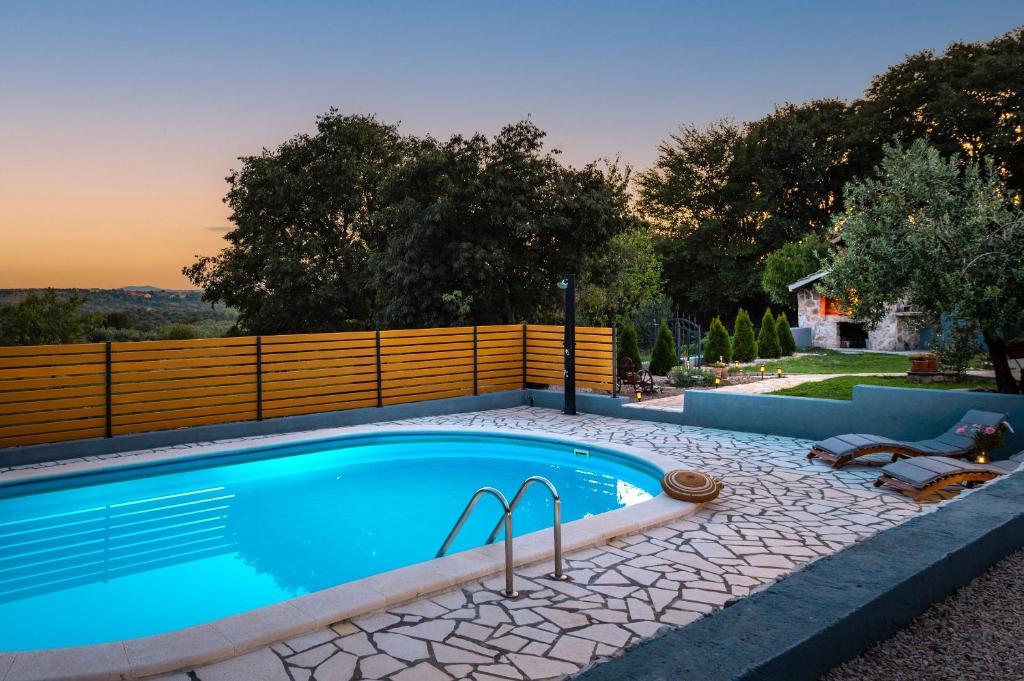 a swimming pool with two chairs next to a fence at Villa Manda Adriatic heated pool in Skradin