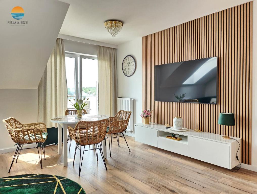 a living room with a table and a television on a wall at Sztutowo Perła Mierzei by Grand Apartments in Sztutowo