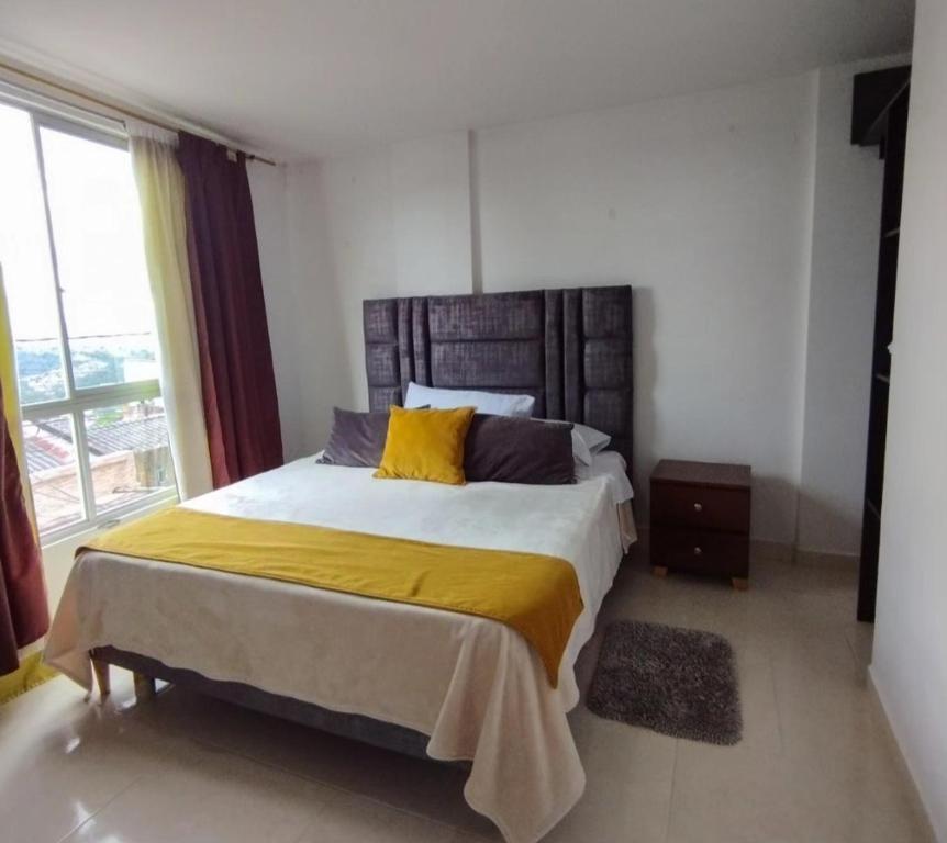 ein Schlafzimmer mit einem großen Bett mit gelben Kissen in der Unterkunft Hotel Guadalupe Home in Pereira