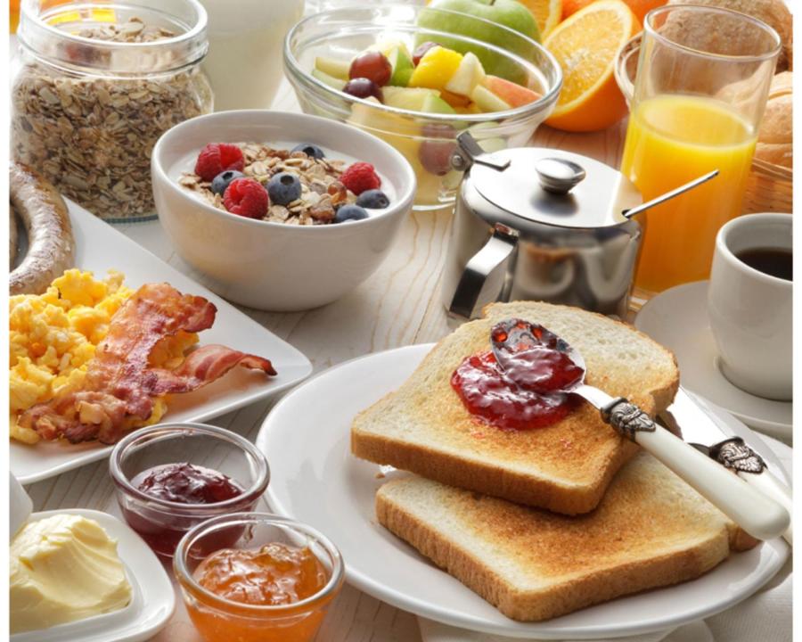 贝宁城Hotel Adonai Ltd的包括烤面包和一盘早餐食品的早餐桌