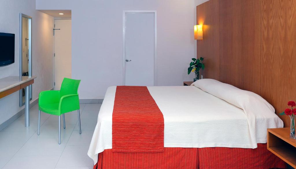 a bedroom with a large bed and a green chair at Adhara Express in Cancún